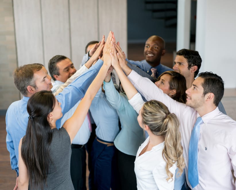 Happy business team celebrating their success at the office with a high five - teamwork concepts