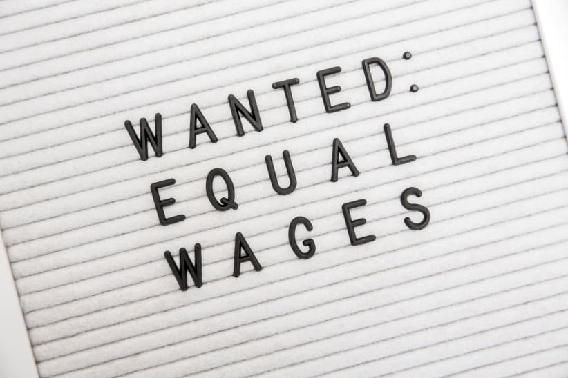 A phrase on a letterboard that says "Wanted: Equal Wages." This phrase depicts the need for equality, equal pay, and the end of job discrimination and sexism.