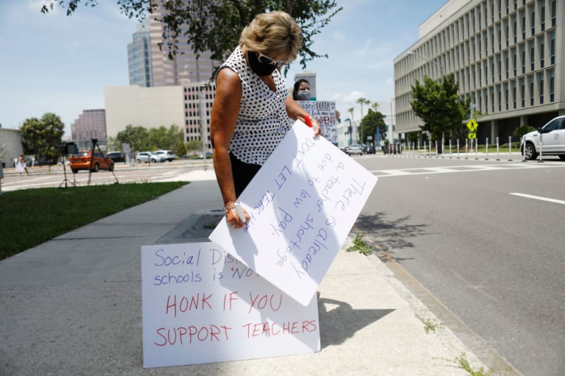 TAMPA, FL - JULY 16: High school math teacher Amy Eaglowski writes a message on a poster board while standing in protest in front of the Hillsborough County Schools District Office on July 16, 2020 in Tampa, Florida. Teachers and administrators from Hillsborough County Schools rallied against the reopening of schools due to health and safety concerns amid the COVID-19 pandemic. (Photo by Octavio Jones/Getty Images)