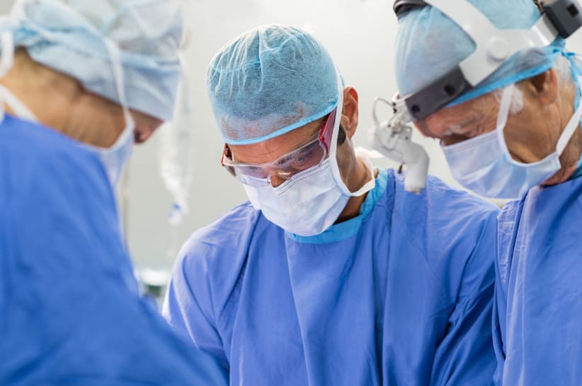 Team of focused surgeon at work on operation in hospital. Medical team performing operation. Mature surgery staff in the operating room working on patient.