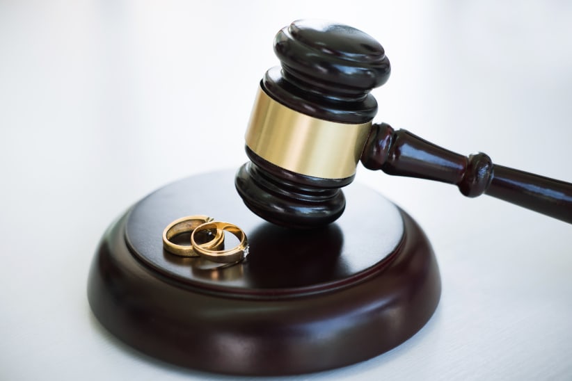 Close up of Judge gavel deciding on marriage divorce and two golden marriage ring.