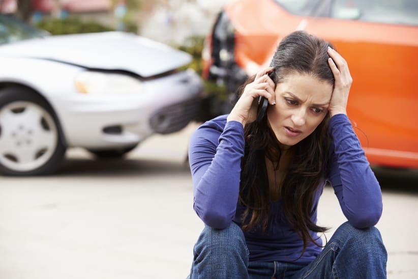 Female Driver Making Phone Call After Traffic Accident With Head In Hands.