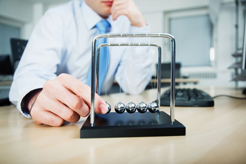 Worker playing with Newton's cradle in office