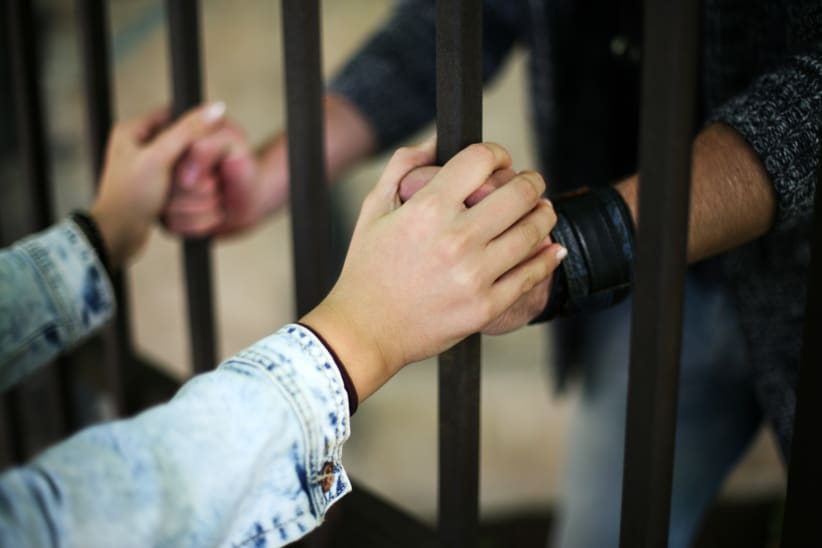 Prisoner holding hands through cell