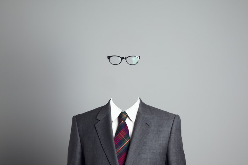 A head and shoulders shot of a business person wearing glasses, but their face is invisible.